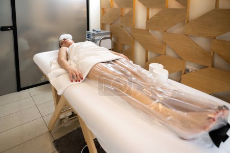 Young woman on Anti-cellulite vacuum slimming treatment with a nylon bag for legs in beauty salon.