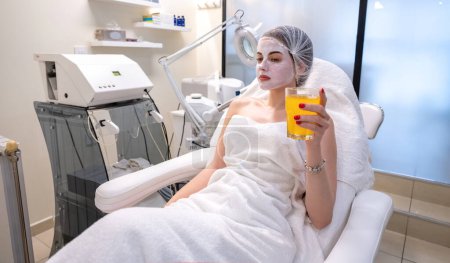 Photo for Beautiful young woman with facial mask relaxing at beauty salon - Royalty Free Image