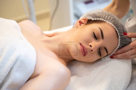 Téléchargez les photos : Jeune femme ayant massage de la tête dans le salon de beauté - en image libre de droit