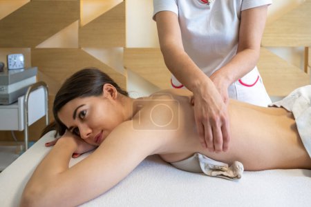 Téléchargez les photos : Vue latérale de belle jeune femme bénéficiant d'un massage dans le spa de santé - en image libre de droit