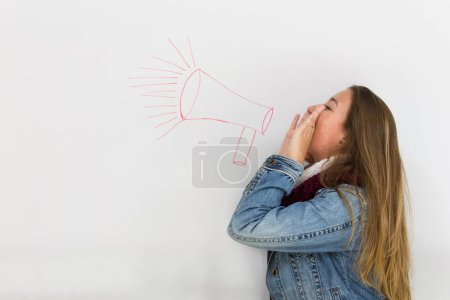 Foto de Chica rubia con las manos en la boca gritando sobre el dibujo de megáfono rojo en la pizarra blanca. Jovencita inconformista gritando. Lucha por tu concepto de derechos - Imagen libre de derechos