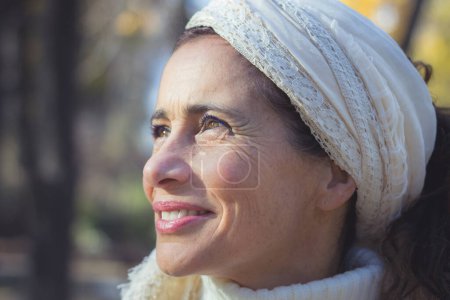 Photo for Portrait of charming middle aged woman with optimistic look in the park. Sunshine on pretty mature lady outdoors with blurred background. Hopeful, positive expression concepts - Royalty Free Image