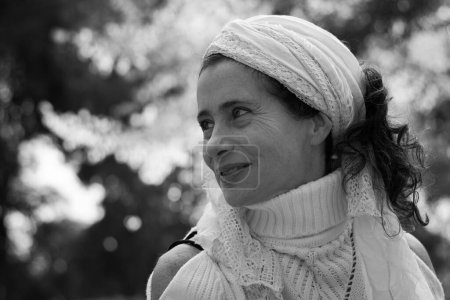 Photo for Black and white portrait of good looking mature woman. Middle aged lady with shawl on head and turtle neck knitted sweater in the park. Hippie style, autumn season, fashion model concepts - Royalty Free Image