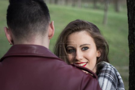 Photo for Brunette girl stands by boyfriend while looking at camera with smile. Cheating concept. Couple having funny conversation - Royalty Free Image