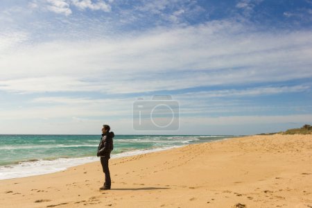 Téléchargez les photos : Lonely young man looking over the ocean at seashore in Zahora Beach, Andalusia, Spain. Thoughtful person alone by the sea. Contemplation, visionary concept - en image libre de droit