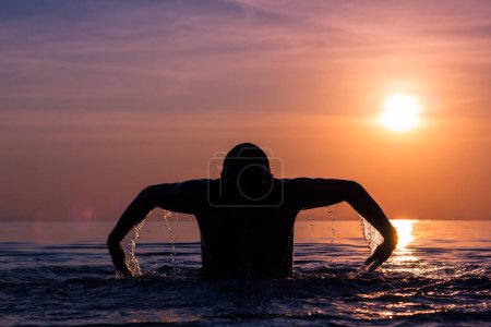 Foto de Silueta de hombre nadando mariposa carrera técnica en espléndido colorido atardecer en la playa en la isla de Koh Phangan, Tailandia - Imagen libre de derechos