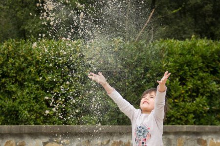 Téléchargez les photos : Funny little girl throwing sand in the air with open arms at park in Bilbao - en image libre de droit