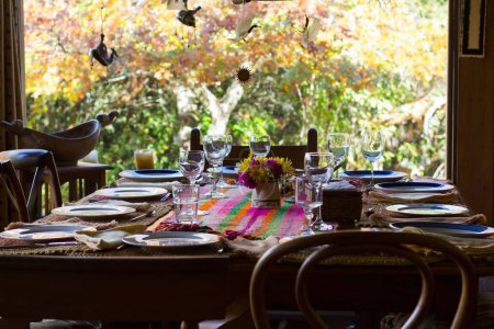 Photo for Wooden chairs and table set for family reunion meal on countryside with green and brown trees on the background outside the window - Royalty Free Image