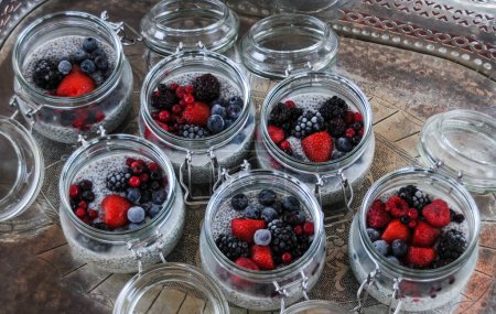 Foto de Seis cuencos de vidrio de semillas de chía pudín con bayas de frutas mixtas sobre fondo de bandeja de plata - Imagen libre de derechos