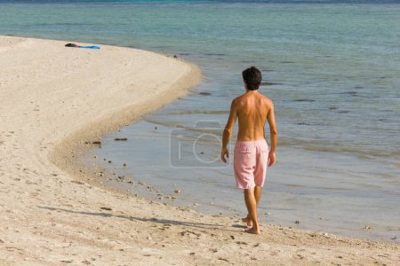 Foto de Hombre en trajes de baño caminando por la costa en forma de S en la playa en la isla de Koh Phangan, Tailandia. Vacaciones de verano, conceptos de destino - Imagen libre de derechos