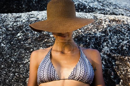 Foto de Modelo mujer posando en sombrero y bikini sujetador cerca de roca - Imagen libre de derechos