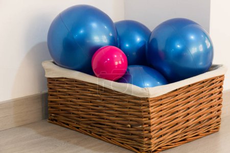 Téléchargez les photos : Balles de pilates de poids bleu et rose dans un panier en osier. Yoga studio accessoires en plastique, équipement, accessoires, formation, exercice intérieur, concepts d'entraînement - en image libre de droit