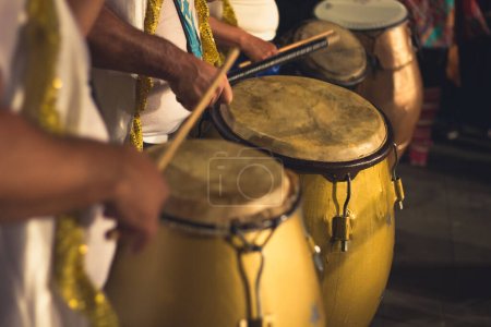 Group of men playing yellow drums at carnival parade at night. Brazil batucada musicians. Party event celebration concept. Loud music performers