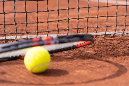 Photo for Tennis ball and racket by net on clay court. Sports tournament competition concept - Royalty Free Image