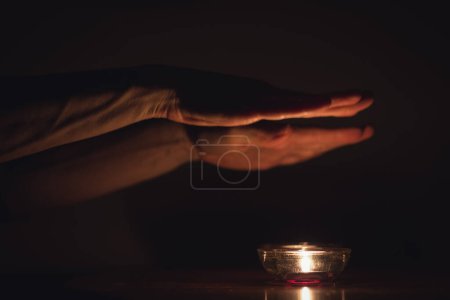 Téléchargez les photos : Sabbat Tradition juive avec des bougies sur la table et les mains sur le dessus priant dans les ténèbres. Effet vintage. Image basse clé - en image libre de droit