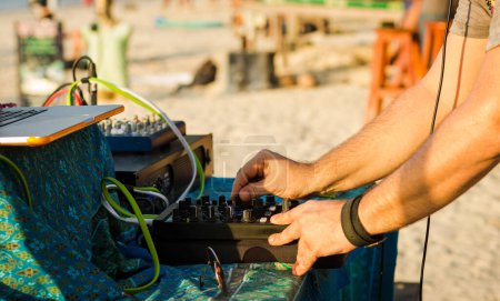 Téléchargez les photos : Gros plan sur DJ jouant de la musique avec un équipement professionnel, y compris console, ordinateur portable et amplificateur de puissance. Fête à la plage au coucher du soleil sur l'île de Koh Phangan, Thaïlande - en image libre de droit