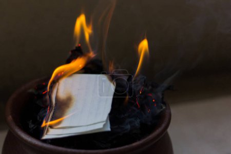 Photo for Letters on fire inside brown clay pot. Memories removal, promise commitment, burning evidence concepts. Papers, documents elimination - Royalty Free Image