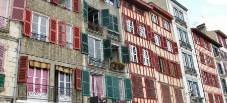 Téléchargez les photos : Façade de maisons colorées avec des fenêtres en bois vert et rouge. Petits balcons dans la ville de Bayonne, Sud de la France - en image libre de droit