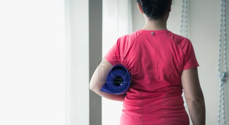 Photo for Back view of woman carrying purple Yoga mat, cropped image - Royalty Free Image