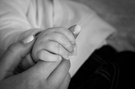 Photo for Small baby hand holds mom's finger with painted nails. Family, love, tenderness, trust, maternity, motherhood concepts. Black and white photography - Royalty Free Image