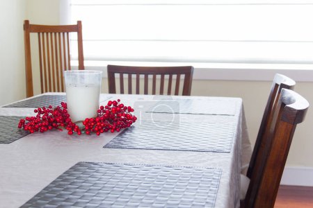 Foto de Bayas rojas un vaso de vela como decoración en la mesa del comedor con sillas de madera al lado de la ventana. Inicio concepto de diseño de interiores - Imagen libre de derechos