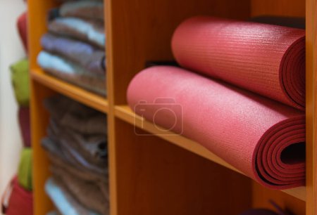 yoga supplies on wooden shelves, yoga blankets 