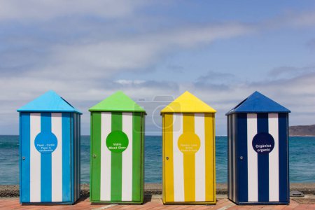 Foto de Coloridos contenedores de reciclaje en la playa de Las Canteras, Gran Canaria. Papel, cartón, vidrio mezclado, ladrillos, plásticos, latas, contenedores orgánicos. Respetuoso del medio ambiente, preocupación por el cuidado del planeta, ir concepto verde - Imagen libre de derechos