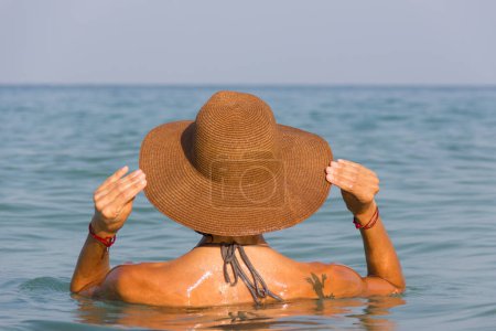 Téléchargez les photos : Modèle de bikini avec chapeau sur la plage face à l'île de Koh Phangan, Thaïlande. Sunblock, concept de soins de la peau - en image libre de droit