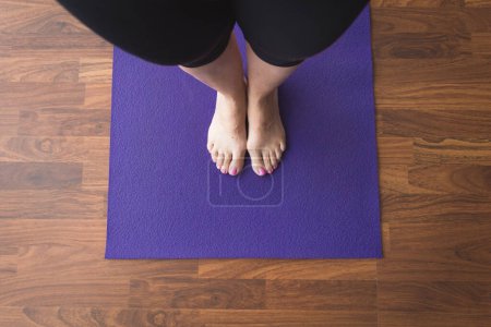 Téléchargez les photos : Femme debout sur le tapis de yoga violet - en image libre de droit