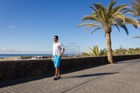 Photo for Young man on Maspalomas walk on early sunny morning. Male tourist enjoying nature views in Gran Canaria island, Spain. Summer vacation, travel destination concepts - Royalty Free Image