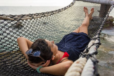 Photo for Happy girl on net hammock bed with sunglasses on her head contemplating the sea in the island of Koh Pha Ngan, Thailand. Success, vacation destination concept - Royalty Free Image
