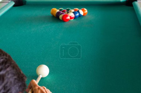 Close up on man from behind about to start a pool table game. Hobby, competition, entertainment concept. Billiards, snooker concept