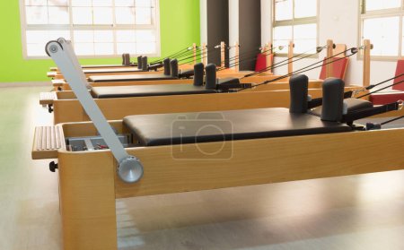 Linie der Pilates-Holzreformer im hellen Studio. Fitnesstraining, Konzepte für Trainingsgeräte