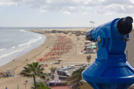 Photo for Blue monocular on viewpoint overlooking Playa del Ingles in Maspalomas, Gran Canaria. Great views of popular beach in Canary Islands. Summer tourism destination. Language translation: one euro coin - Royalty Free Image