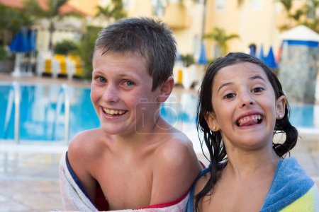Photo for Little boy and girl smiling with funny faces wrapped up in towels by swimming pool. Happy brother and sister keeping warm and dry at summer resort vacation. Fun holidays, leisure time concepts - Royalty Free Image