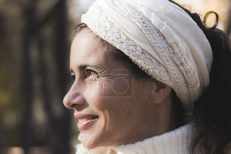 Foto de Portrait of charming middle aged woman with optimistic look in the park. Sunshine on pretty mature lady outdoors with blurred background. Hopeful, positive expression concepts - Imagen libre de derechos