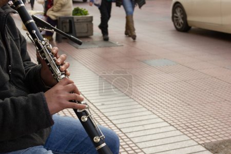 Foto de Primer plano de las manos de un joven tocando el clarinete en la calle mientras los peatones pasan por el centro de La Serena, Chile. Músico infravalorado, conceptos de artista - Imagen libre de derechos