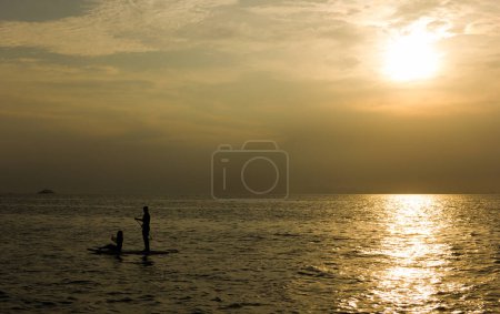 Foto de Silueta de una pareja sobre tabla de remo en mar abierto al atardecer en la isla de Koh Pha Ngan, Tailandia - Imagen libre de derechos
