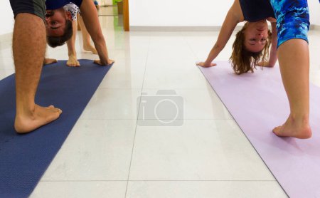Téléchargez les photos : Homme et femme s'étirant au cours de yoga, pieds nus sur des nattes - en image libre de droit
