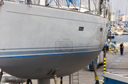 Foto de Barco gris y blanco en andamios para reparar. Club náutico, concepto de muelle - Imagen libre de derechos
