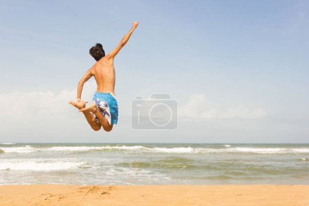 Téléchargez les photos : Jeune homme faisant un saut acrobatique sur une plage vide à Bentota, Sri Lanka. Liberté, voyage d'été concept d'aventure - en image libre de droit