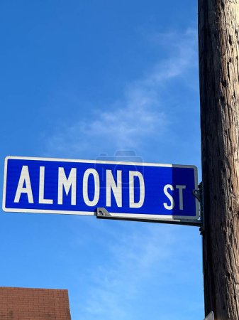 Téléchargez les photos : Panneau de rue amande blanche et bleue sur poteau téléphonique sur fond bleu ciel. - en image libre de droit