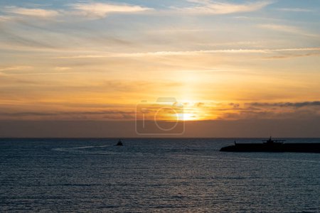Foto de En la fotografía se puede ver una puesta de sol en la hora azul con un remolcador saliendo del puerto. - Imagen libre de derechos