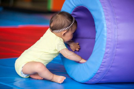 Foto de Retrato de una hermosa niña feliz de diez meses jugando sobre un fondo colorido. Estimulación temprana para el concepto de niños pequeños. - Imagen libre de derechos