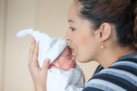 Foto de Joven hermosa madre en el hospital besando a su niña recién nacida en el día de su nacimiento. Concepto de maternidad - Imagen libre de derechos