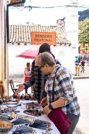 Photo for Bogota, Colombia - July 2nd 2023. Tourist buying products from an street artist  at the famous La Candelaria neighborhood at Bogota city center. - Royalty Free Image