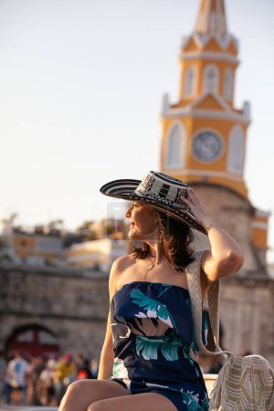 Schöne Frau mit dem traditionellen kolumbianischen Hut namens Sombrero Vueltiao am Uhrturm in den historischen Straßen der von Mauern umgebenen Stadt Cartagena de Indias