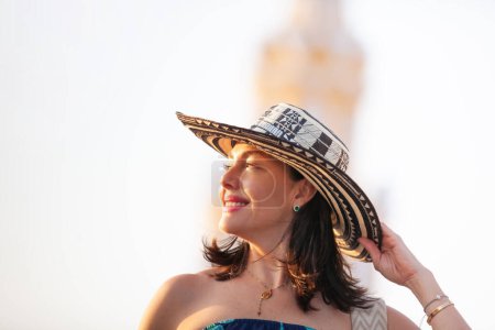 Hermosa mujer vestida con el tradicional sombrero colombiano llamado Sombrero Vueltiao en la Torre del Reloj en las calles históricas de la ciudad amurallada de Cartagena de Indias