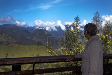 Turista senior mirando los increíbles paisajes de las Cordilleras Centrales en el ascenso a la Alta de Letras entre las ciudades de Fresno y Manizales en Colombia