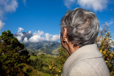 Turista senior mirando los increíbles paisajes de las Cordilleras Centrales en el ascenso a la Alta de Letras entre las ciudades de Fresno y Manizales en Colombia